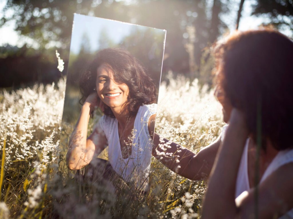 woman in front of a mirror smiling. Throat Chakra.