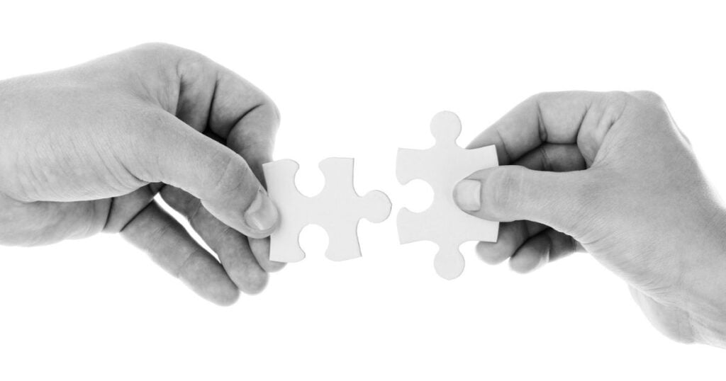 hands holding two puzzle pieces