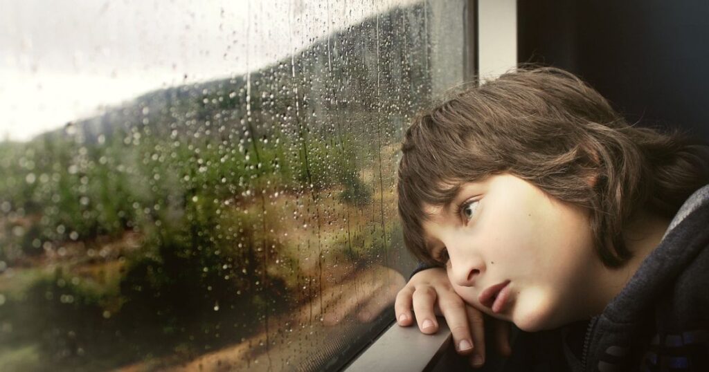 boy watching the rain out the window