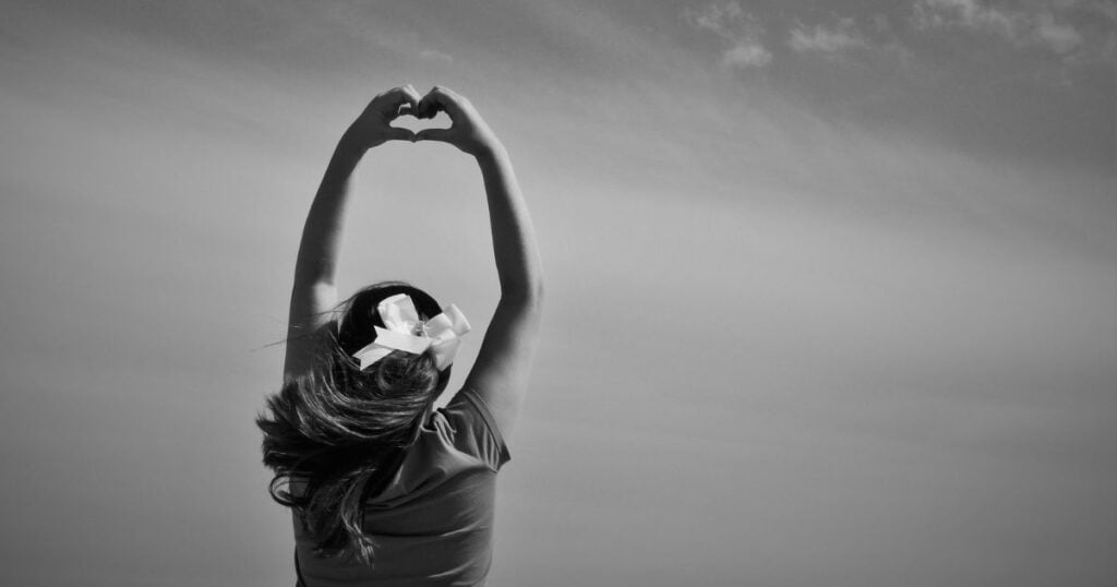 woman making a heart with her hands to have energy healing superpower.
