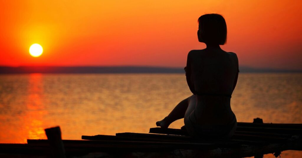 shadow of a woman sitting watching the sunset